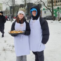 Uczniowie częstują ciasteczkami uczestników Orszaku