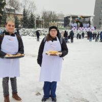 Uczniowie częstują ciasteczkami uczestników Orszaku