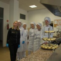 Uczennice z nauczycielką prezentują pracownię cukierniczą